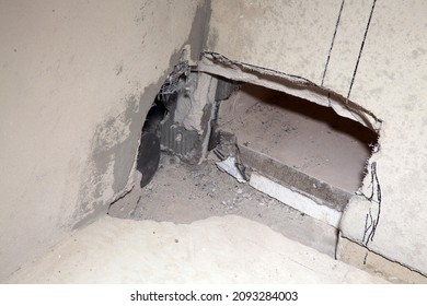 Hole in the wall. Opening. Port, aperture, orifice, slot. Drilling marks. Stones on the floor, broken floor, devastation, screed, floor repair. Concrete wall in the room. Cement. Bare walls. Dirt Dust - Shutterstock ID 2093284003