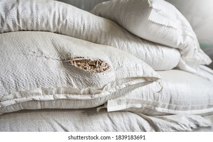 A Hole In A White Bag With Animal Feed In A Warehouse