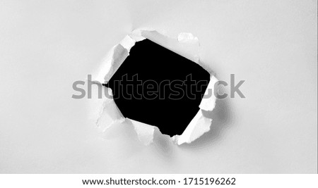 A hole in white paper with torn edges and a black isolated background inside, Ripped black and white paper, copy space