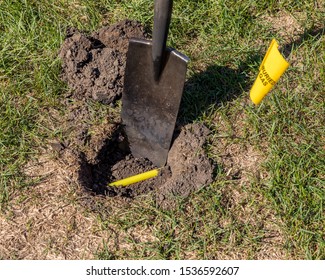 Hole In Yard With Yellow Plastic Natural Gas Line Buried In Ground, Shovel And Natural Gas Warning Flag. Concept Of Notify Utility Locating Company For Underground Utilities Before Digging For Safety