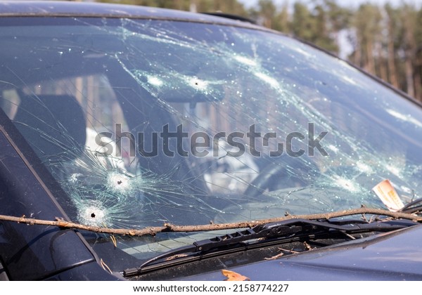 Holes on the windshield\
of the car, it was shot from a firearm. Bullet holes. Smash car\
windshield, broken and damaged car. The bullet made a cracked hole\
in the glass