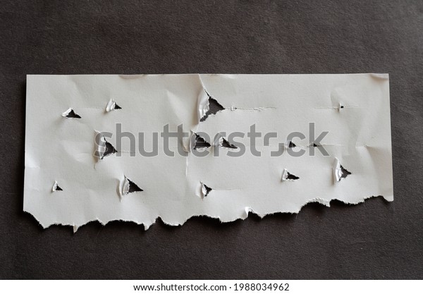 Holes and\
scratches on white paper. Ripped, crumpled sheet of paper on gray\
background. Abstraction,\
minimalism.