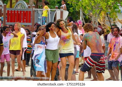 HOLI FESTIVAL OF COLOURS, MALDIVES HIMMAFUSHI, AUGUST 2019: Man takes photos of three female tourists having fun at a festival of colors in the Maldives. Tourists having fun at a holi festival party.