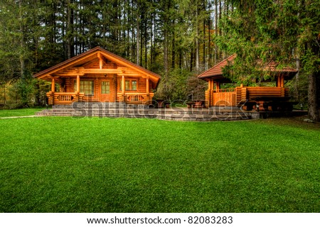 Holiday apartment - wooden cottage in forest in early spring with green grass on back yard and forest in background