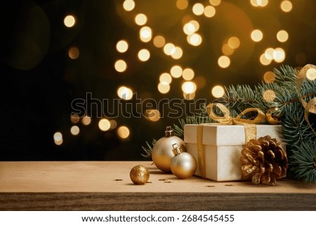 Holiday background with gift box, pine branches, cones and baubles on wooden table. Warm golden bokeh and copy space for greeting cards, banners and promotions.