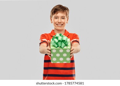 Holiday, Birthday Present And People Concept - Portrait Of Happy Smiling Boy In Red Polo T-shirt With Gift Box Over Grey Background