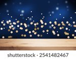 Holiday blue background with an empty wooden table, lights, and snow.