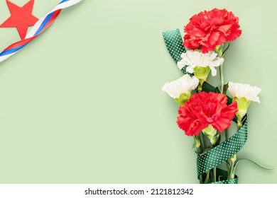 Holiday Card With Red And White Carnations With Russian Flag Gift Ribbon And Red Star On A Green Background With Copy Space For Congratulatory Text Suitable For 23 February, 9 May Or Day Of Russia