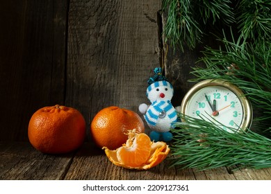 A holiday card with toys and tangerines. Green branches with a clock and a snowman close-up - Powered by Shutterstock