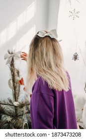 Holiday Christmas Decorating At Home. Young Woman Putting Ornaments On Xmas Tree, Setting Up Lights. Budget Hristmas Home Decor Ideas