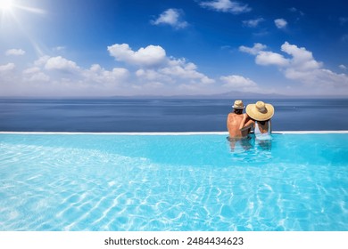 A holiday couple in a big infinity pool enjoys the panoramic view to the blue sea during summer vacation time - Powered by Shutterstock