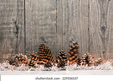 Holiday decoration with Christmas lights and cones over wooden background