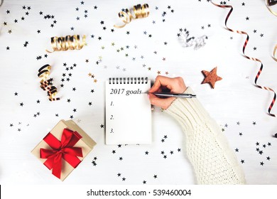 Holiday decorations and notebook with 2017 goals on white rustic table, flat lay style. Christmas planning concept. - Powered by Shutterstock