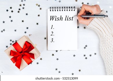 Holiday Decorations And Notebook With Wish List On White Rustic Table, Flat Lay Style. Planning Concept.