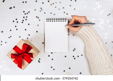 Holiday Decorations And Notebook With Wish List On White Rustic Table, Flat Lay Style. Planning Concept.