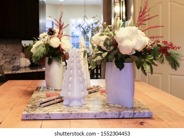 Holiday Floral Center Pieces With White Roses, Red Accents And Greenery On A Large Butcher Block And White Granite Kitchen Island