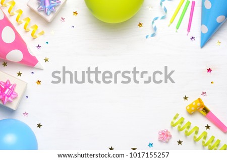 Holiday frame or background with colorful balloon, gift, confetti, silver star, carnival cap and streamer. Flat lay style. Birthday or party greeting card with copy space.