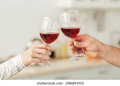 Holiday greetings, date at home and romantic evening. Domestic life and anniversary. Adult european man and female clink glasses with red wine in minimalist kitchen interior, empty space, cropped