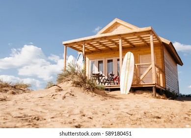Holiday house on the beach. Wooden house with boards for wind serfing on a sand beach. Summer vacation concept. - Powered by Shutterstock