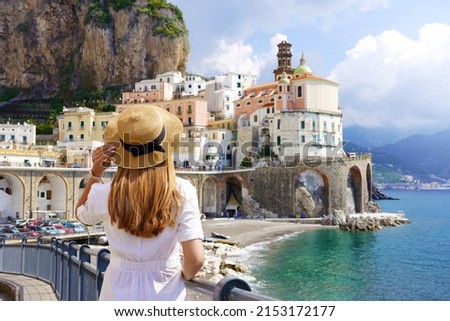 Holiday in Italy. Back view of young woman with white dress and hat looking the village of Atrani on Amalfi Coast, Italy.