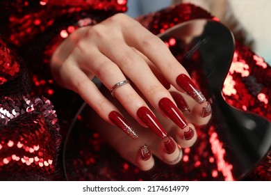 Holiday manicure on long square nails with Golden sequins, black shiny nail Polish and craquelure matte black coating. - Shutterstock ID 2174614979