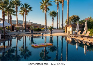 Holiday Mode. Beautiful Picture Of Colorful Landscape, Blue Sky And Its Reflection On Turquoise Water Like In A Mirror. Tropic Palms Garden And Luxury Pool, No People. Yellow Air Mattress On Water