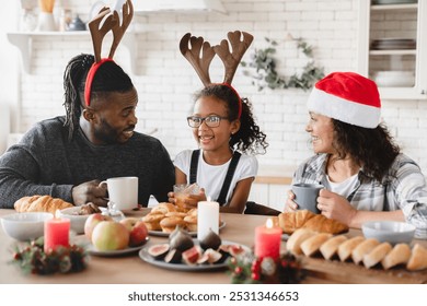 Holiday morning breakfast. African-american family of three with small daughter celebrating Christmas New Year together at home kitchen. - Powered by Shutterstock