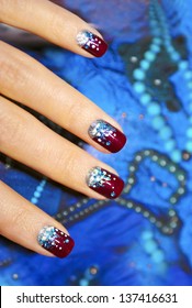 Holiday nails with a manicure with claret varnish and sparkles on the decorative background.
