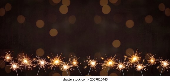 Holiday New Year's Eve Silvester New Year Party Birthday Wedding festive background banner greeting card	- Many burning sparkler in the dark black night with bokeh golden light