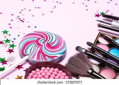 Holiday Party Makeup Cosmetics. Color Glitter Eyeshadow, Blush, Liquid Eyeliner, Mascara, Brushes With Lollipop And Confetti. Shallow Depth Of Field, Copy Space