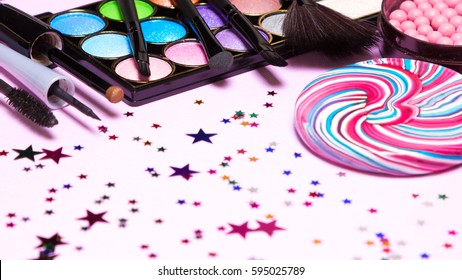 Holiday Party Makeup Cosmetics. Color Glitter Eyeshadow, Blush, Liquid Eyeliner, Mascara, Brushes With Lollipop And Confetti. Shallow Depth Of Field, Copy Space