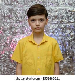 Holiday Photo Concept For Teenager Boy. Portrait Of A Baby Boy On A Shiny Background In A Yellow Shirt. Stands In Front Of The Camera In Different Poses With Emotions.