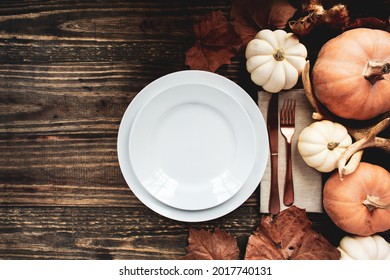 Holiday place setting with plate, napkin, and silverware on a Thanksgiving Day decorated table shot from flat lay or top view position. Pumpkins, antlers and fallen leaves. 