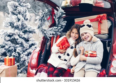 Holiday Preparations. Pre Teen Children Enjoy Many Christmas Presents In Car Trunk. Cold Winter, Snow Weather.