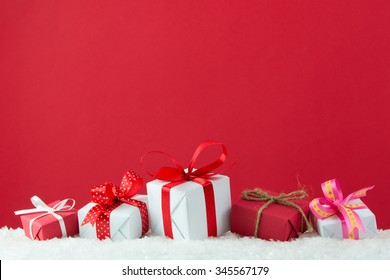 Holiday presents with ribbon in a row on snow with red color background