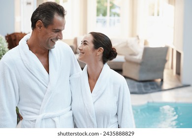 Holiday, robe and couple at hotel pool with smile, embrace and relax together at wellness spa getaway. Hospitality, happy woman and man at luxury villa for travel, vacation and love on romantic date - Powered by Shutterstock