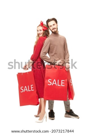 Holiday sale. Full length portrait of a couple fashionable young people posing with purchases on a white background with copy space. Shopping on holidays. Christmas sale.