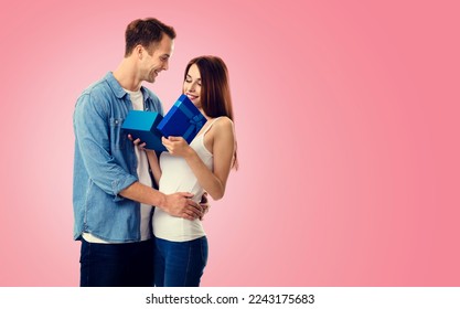 Holiday sales actions, rebates, discounts offers concept image -  happy smiling amorous couple opening gift box. Isolated on vivid rose pink background. Copy space for text. Valentines, 14 February