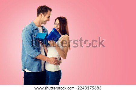 Holiday sales actions, rebates, discounts offers concept image -  happy smiling amorous couple opening gift box. Isolated on vivid rose pink background. Copy space for text. Valentines, 14 February