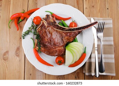 holiday savory : roasted beef spare rib on white dish with cutlery thyme pepper and tomato on wooden table