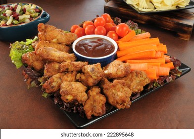 A Holiday Snack Platter With Chicken Wings, Carrot Sticks, Cherry Tomatoes, Salads, And Chips