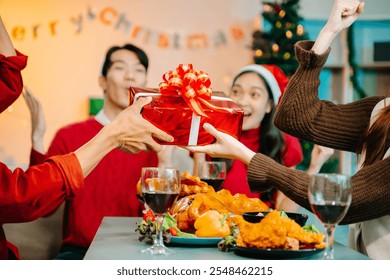 Holiday spirit with Asian friends exchanging gifts, sharing laughs, and enjoying a festive Christmas dinner in a cozy, joy filled setting. - Powered by Shutterstock