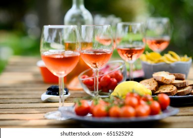 Holiday Summer Brunch Party Table Outdoor In A House Backyard With Appetizer, Glass Of Rosé Wine, Fresh Drink And Organic Vegetables  