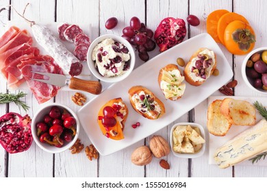 Holiday Themed Appetizer Table Spread With Assorted Cheeses, Meats And Crostini. Above View On A White Wood Background.