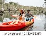 Holiday travel activities. Happy asian couple man and woman rowing a canoe or kayak in mangrove forests. Young traveler with kayak at botanical garden tropical mangrove forest in a national park.