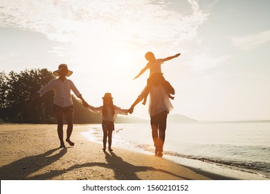 Holiday travel concept, Summer vacations. Happy family are having fun on a tropical beach in sunset. Father and mother and children playing together outdoor on sea.