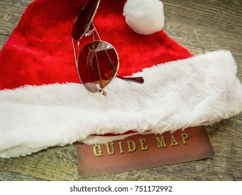 Holiday Travel Guide Background. Holiday Travel Concept With Santa Hat, Aviator Sunglasses And A Map For Surviving The Busy Holiday Travel Season.
