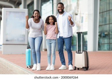 Holiday Trip After Lockdown. Full body length portrait of excited African American mum, daddy and daughter going on a journey. Family shaking clenched fists, making win gesture, standing near airport - Shutterstock ID 2000069264