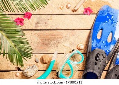 Holiday (vacation) tropical beach background layout with snorkeling theme and free text space. Flippers, goggles and snorkel on sand - diving equipment from above.