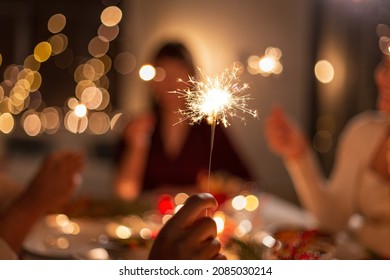 holidays and celebration concept - close up of hand with burning sparkler at christmas dinner party - Powered by Shutterstock